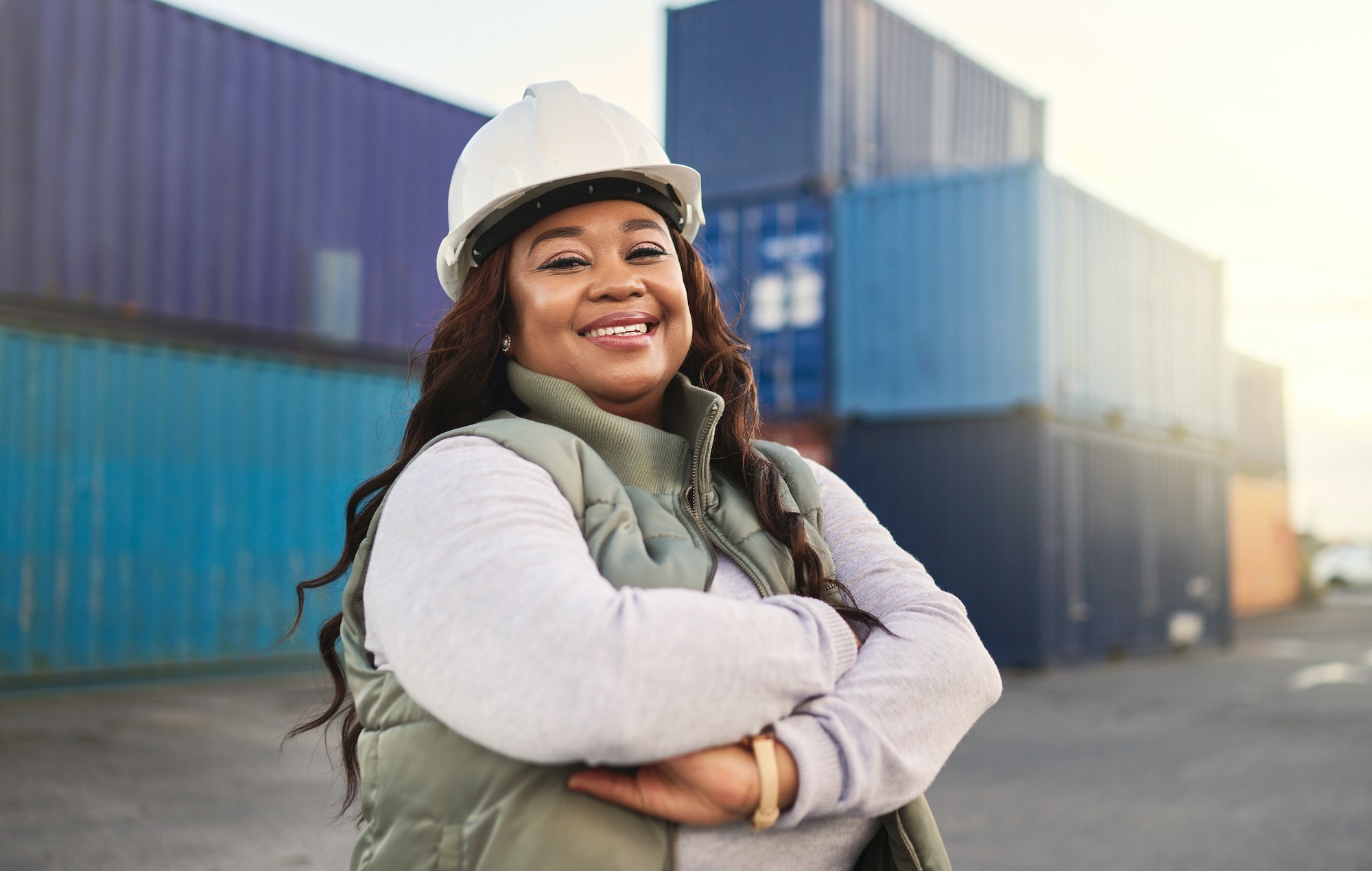 Black woman, smile and work in logistics with container stack at shipyard. Woman, happy and confide